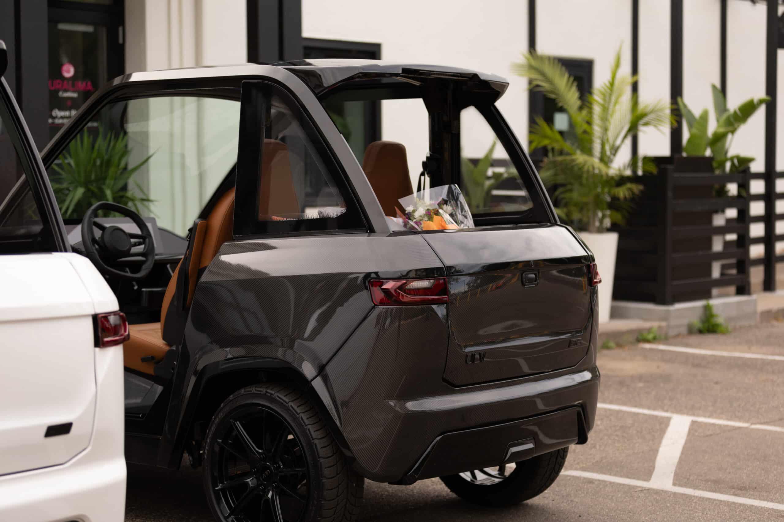 ULV 322 carbon in black parked at a shop with flowers stored in the back of the vehicle.